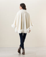 Woman wearing Fur Trimmed Cashmere Cape Petite Length in white. Color: Cervinia Petite