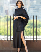 Woman wearing a formal dress with a Aura Lightweight Cashmere Sequin Wrap in black against a cityscape background