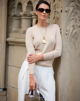 Model leaning against a wall wearing Pura Baby Cashmere Crew Neck Sweater in oatmeal