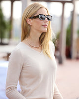 model wearing Pura Baby Cashmere V-Neck Sweater in oatmeal and sunglasses, sideview