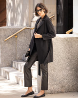 Woman in Bella Cashmere belted Coat in black and pants standing on steps outdoors
