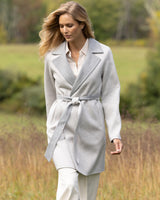 Woman wearing a cashmere wrap coat in grey walking in a field