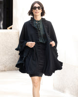 Woman wearing a Knitted Cashmere Cape in Black with ruffles, pencil skirt and blouse on city sidewalk