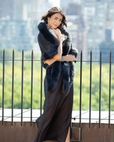 Woman wearing a Fur Trimmed Cashmere Shawl in black over a long dress with a cityscape background