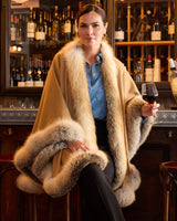 Woman wearing golden island silver fur trimmed cervinia while holding a glass of wine at a bar