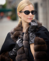 Close up of a model wearing leather gloves and Imperial Sable Cashmere Cape in black