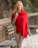 Woman wearing Cashmere water weave wrap with fringe in red outdoors on a stone path