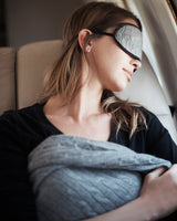 Cable Knit cashmere Travel Set in Grey; mask and blanket on model sleeping on airplane