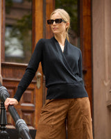 Model on a stoop wearing Élan Faux Wrap Cashmere Sweater in black