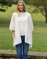 woman on patio wearing Divina Double Knit Cashmere Cape in ivory and jeans