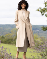 Woman wearing a camel hair Princess Coat in Blonde standing in a scenic outdoor setting with mountains and lavender.