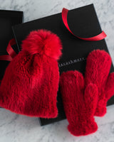 Mink Hat with Fox Fur Pom and matching mittens in red on top of gift box