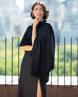 Woman wearing Radiant Cashmere Sequin Wrap in black with a cityscape in the background