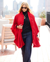 Woman walking on rooftop wearing sunglasses and volant knit cape in red