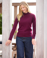 Model standing on a rooftop wearing jeans and Aveline Ruffle Mock Neck Cashmere Sweater in bordeaux
