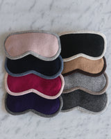 eight cashmere sleep/eye masks laid on white marble in various colors
