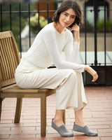 Woman in a plain top and pants outfit sitting on a wooden chair outdoors cashmere slippers in grey