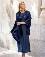 Woman wearing a formal dress and Lightweight Cashmere Wrap in Navy standing against a stone wall.