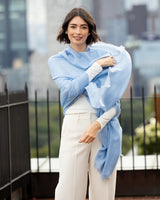 woman wrapping Lightweight Cashmere Wrap in Sky Blue around herself