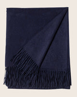 Navy blue throw blanket with fringes on a beige background