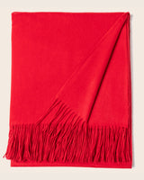 Red blanket with fringes on a beige background