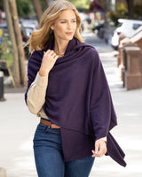 Woman wearing a Voyage Cashmere Wrap in Currant outdoors on a city street.