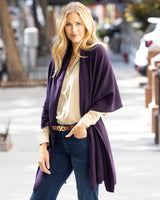 Woman wearing Voyage Cashmere Wrap in Currant over a button down shirt and jeans on a city street.