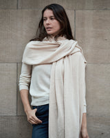 Woman wearing Voyage Cashmere Travel Wrap in oatmeal leaning against wall