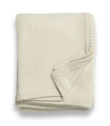 A folded beige cashmere throw blanket with a ribbed texture edges in ivory.