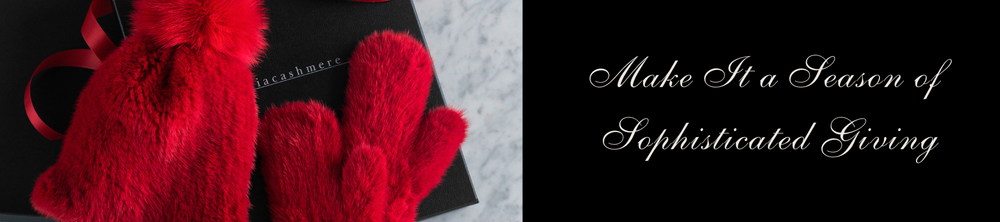 Red mittens and a black box with a bow on a textured surface, accompanied by text 'Make It a Season of Sophisticated Giving'.