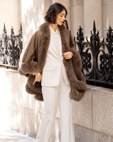 Woman wearing a Cervinia fur trim cape in Sable over a business suit outfit in an urban setting
