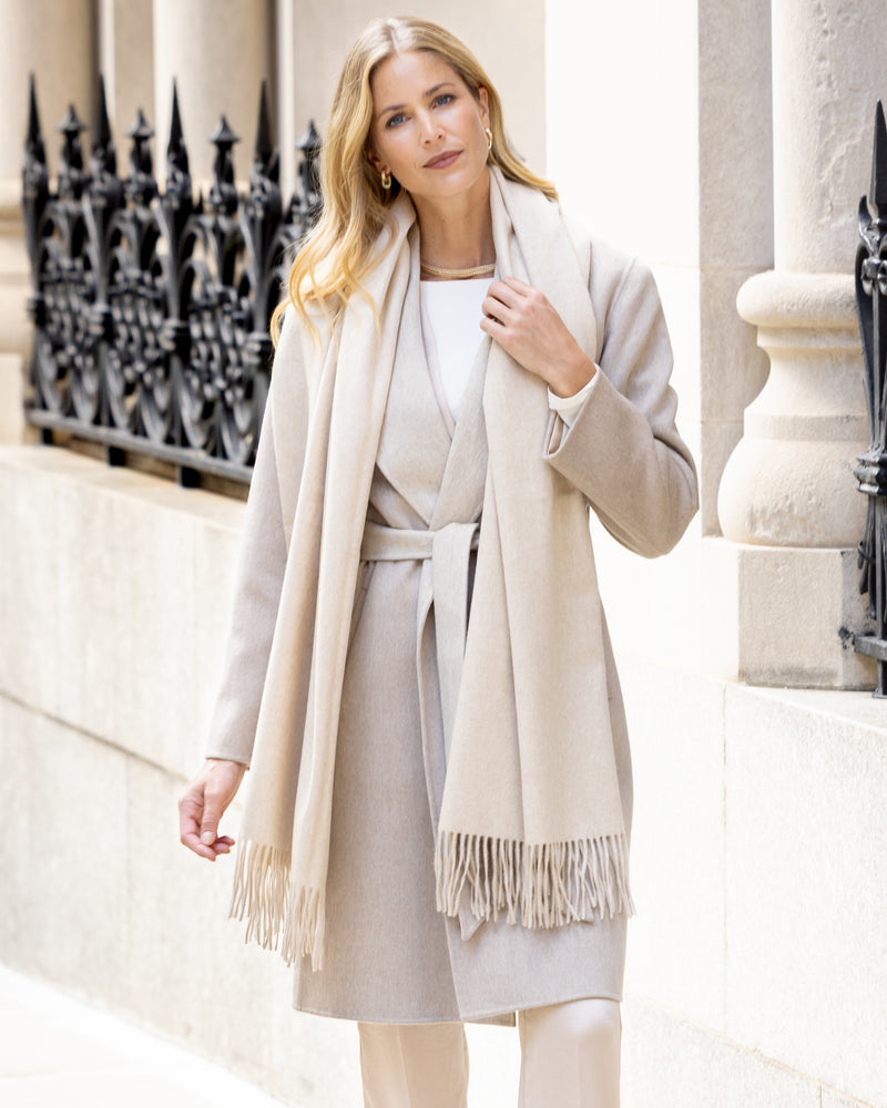 Woman wearing Gabriella cashmere wrap coat with belt in Oat/Beige in an urban setting