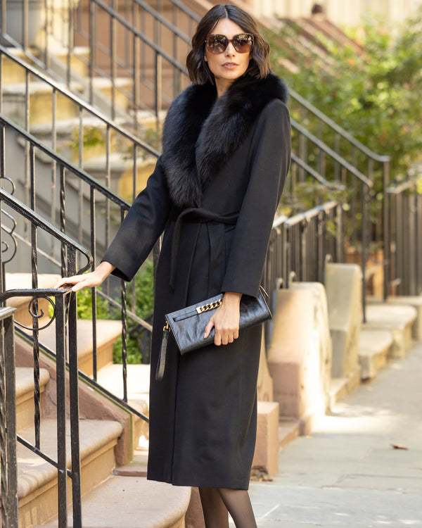 Woman in a Wool Cashmere Blend Maxi Wrap coat with Oversized Finland Fur Shawl Collar  in Black standing on outdoor steps.
