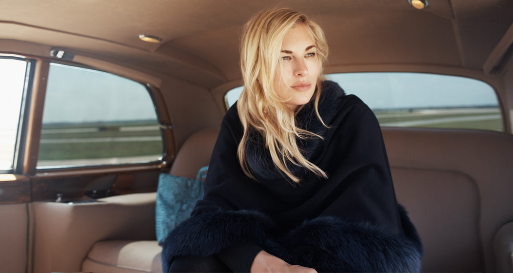 woman sitting in backseat of car wearing Cervinia Fur Trimmed Cashmere Cape Classic Length