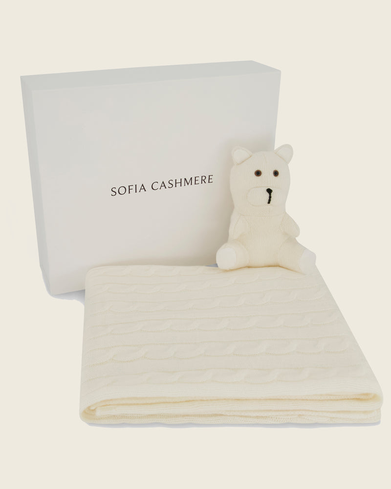 Sofia Cashmere product with a folded cashmere blanket in ivory and a cashmere teddy bear 