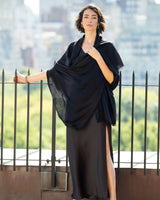 Woman wearing a dress with Lightweight Cashmere Wrap in Black  in an urban setting