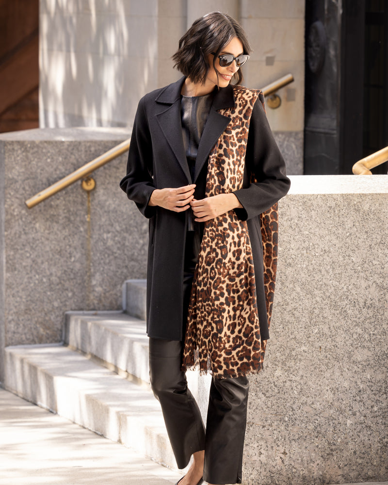 Woman wearing a dark coat and Lightweight cashmere wrap in camel leopard outdoors.