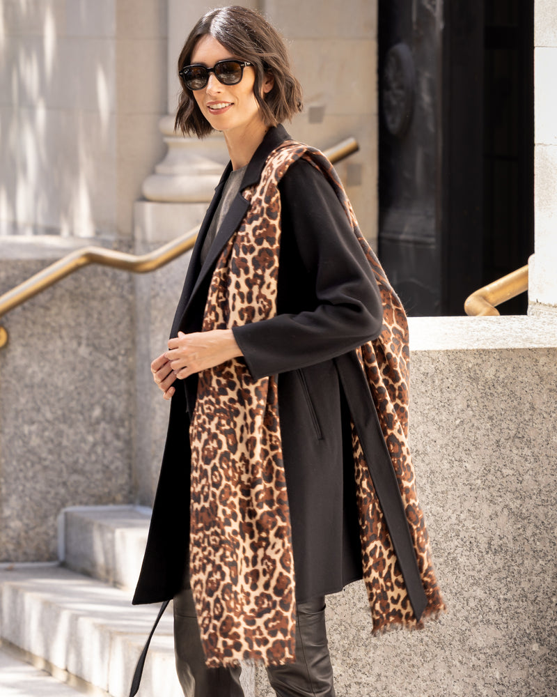 Woman wearing a dark coat with Lightweight cashmere wrap in camel leopard in an urban setting