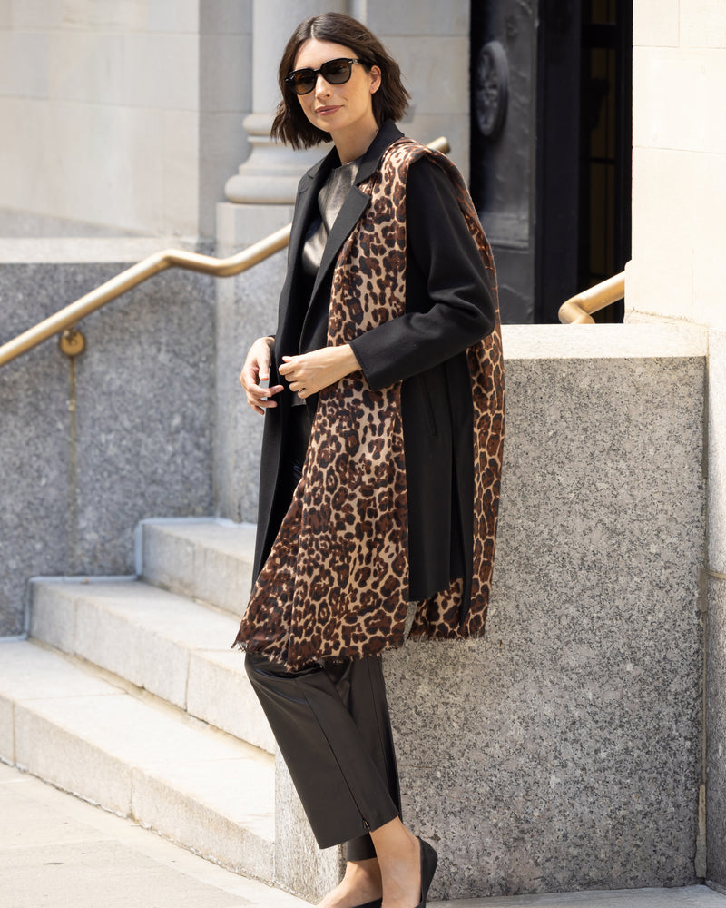 woman wearing Lightweight cashmere wrap in camel leopard leaning on stone wall