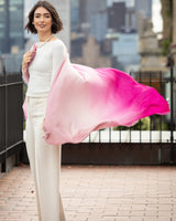 Woman holding a Lightweight Cashmere Wrap in pink ombre with a cityscape in the background