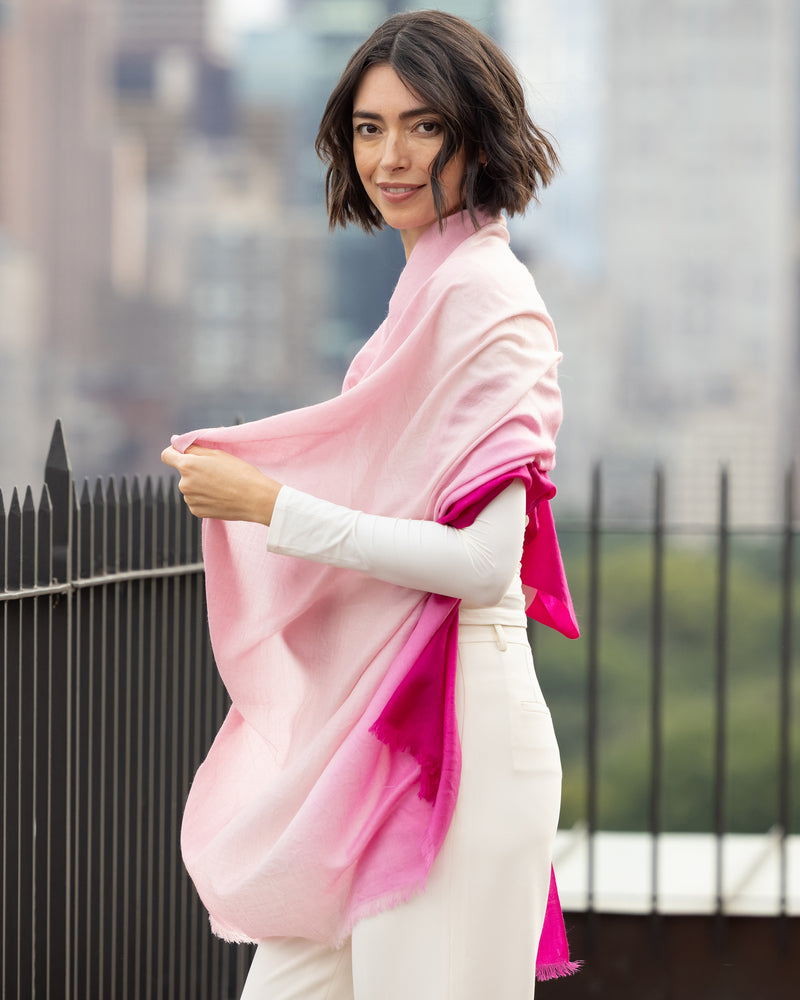 Woman wearing a Lightweight Cashmere Wrap in pink ombre with a blurred background