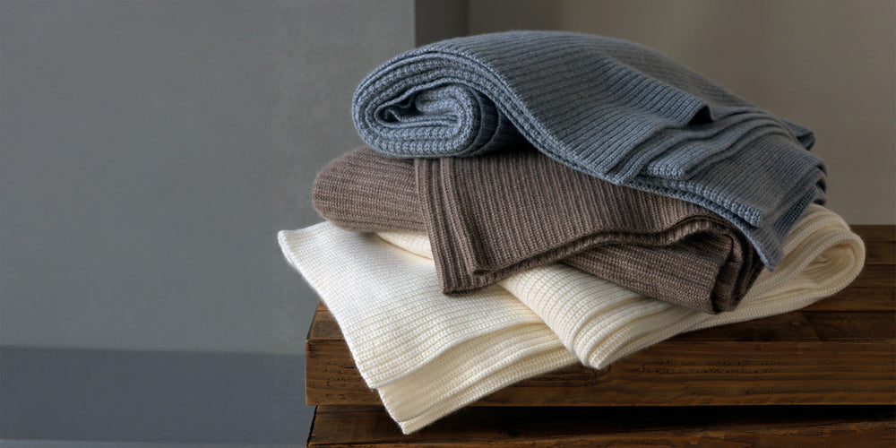stack of cashmere throws on wood table