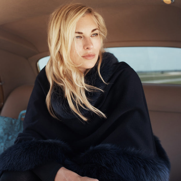 woman sitting in backseat of car wearing Cervinia Fur Trimmed Cashmere Cape Classic Length