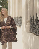 woman walking wearing Roma Wild Reversible Cashmere Cape in Leopard Camel/Brown