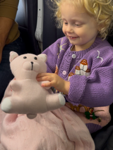 small female child playing with snuggly cashmere teddy bear on airplane