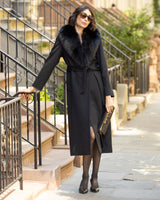 Woman in a Wool Cashmere Blend Maxi Wrap coat with Oversized Finland Fur Shawl Collar  in Black standing on a city street.
