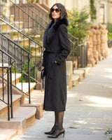 Woman in a Wool Cashmere Blend Maxi Wrap coat with Oversized Finland Fur Shawl Collar  in Black standing on a city street.