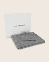 Cable knit baby blanket and pom-pom hat set in light grey, neatly packed in gift box
