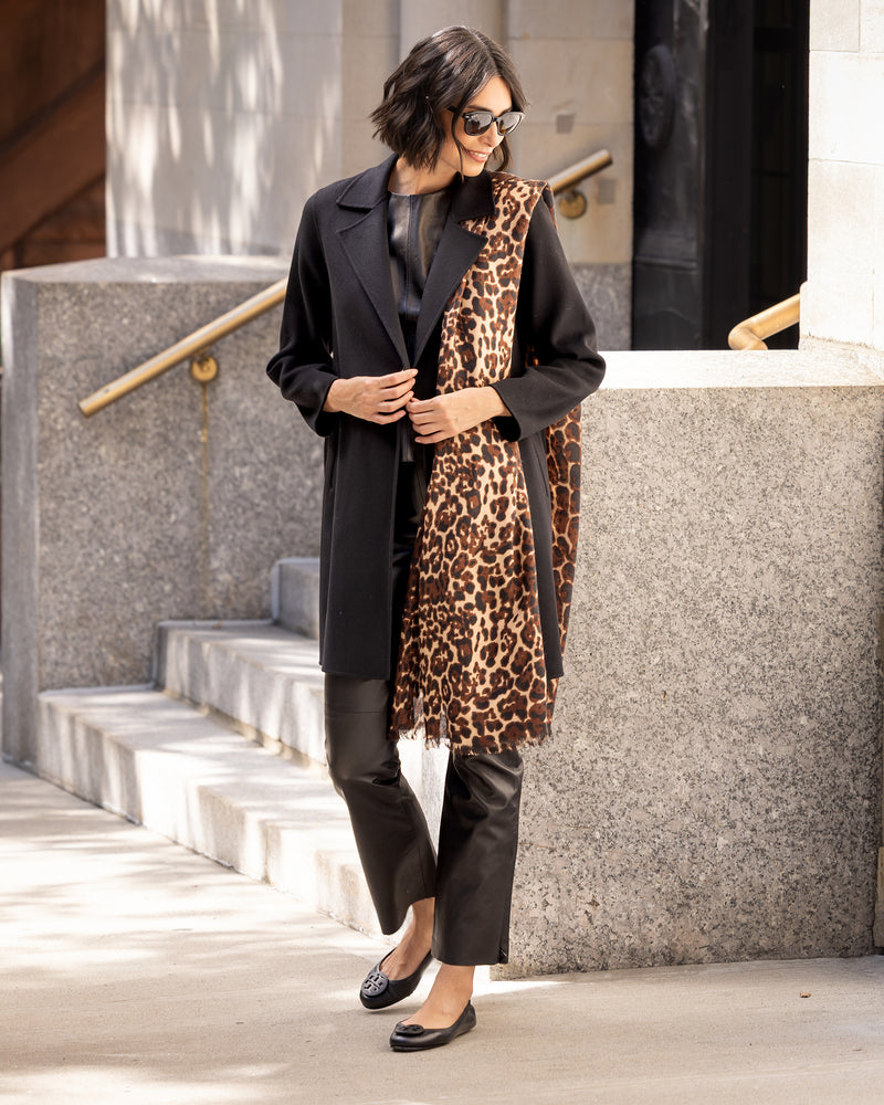 Woman in Bella Cashmere belted Coat in black and cashmere leopard print scarf standing on steps outdoors.