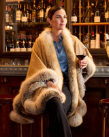 Woman wearing golden island silver fur trimmed cervinia while holding a glass of wine